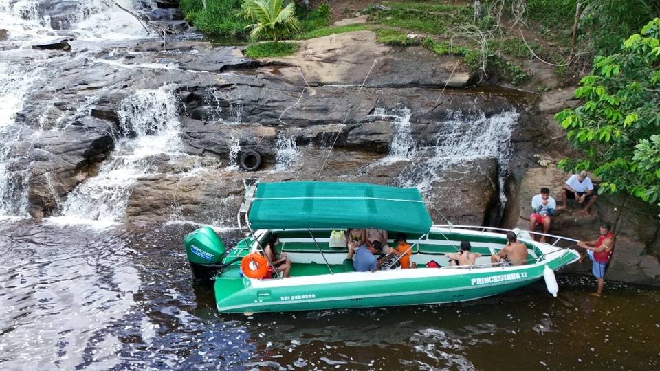 Lancha com passageiros parada ao pé de uma cachoeira